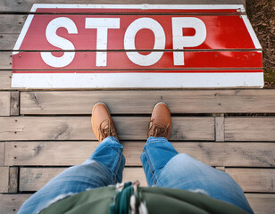 Man standing on the wooden boards with red stop message on the floor, point of view perspective used.	
