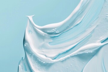 Wall Mural - A blue and white swirl of cream is spread across a blue background. The cream appears to be a light blue color, and it looks like it's been applied to the skin. The image has a calming