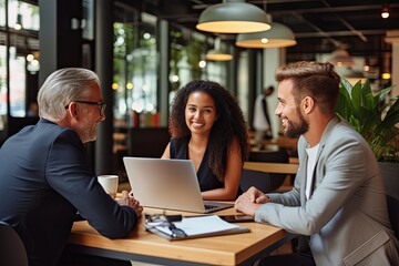 Wall Mural - a group of people sitting around a table with laptops, A team of individuals gathered at a table, each with their own laptop in front of them.