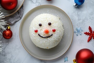 Wall Mural - Christmas snowman face decorated rice cake on a white plate, in a top view, with red and blue decorations around, in natural light.