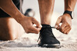 © peopleimages.com - Runner, hands and tying shoes in outdoor for cardio, workout, endurance training or marathon challenge. Closeup, sneakers and feet of male athlete ready for running, fitness or morning exercise