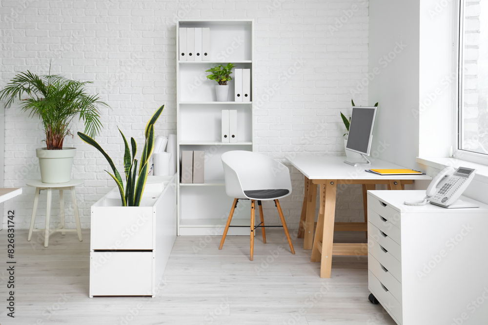 Interior of office with table, shelf unit and plants