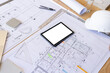 © Wavebreak Media - Architectural plans and drawings spread out on table with a tablet in center