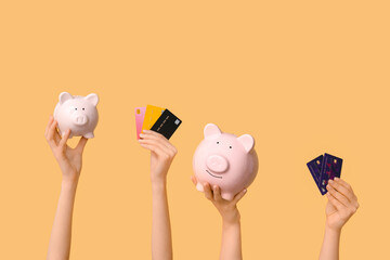 Poster - Female hands with credit cards and piggy banks on yellow background