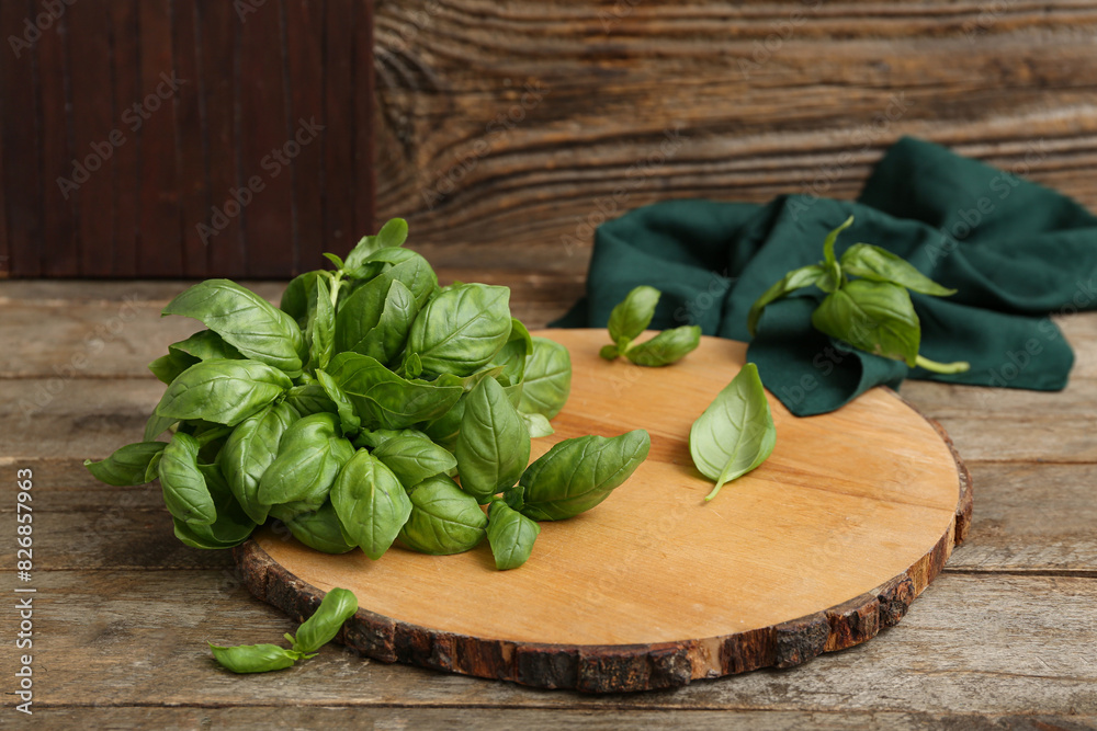 Board with fresh green basil leaves on wooden background