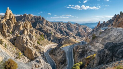 Wall Mural - A dramatic mountain road with hairpin bends, surrounded by jagged rock formations and a clear blue sky overhead 32k, full ultra hd, high resolution
