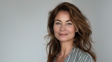 Poster - A business woman against a white background, wearing a striped blouse and smiling confidently