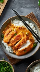 Wall Mural - Delicious rice with golden brown chicken cutlet and creamy curry. The food is served in a bowl with chopsticks.