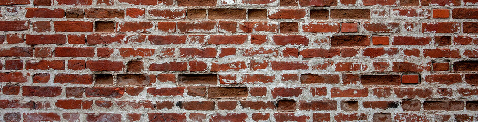 Fragment of old brickwork, wide plan. A wall of red brick. Potholes and defects in a brick wall, side view.