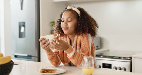 Canvas Print - Child, sandwich and eating food in home kitchen or healthy nutrition with orange juice, student or breakfast. Girl, kid and morning hungry or bread snack in apartment for fiber meal, diet or youth