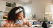 © peopleimages.com - Little girl, student and writing with book in kitchen for homework or assessment at home. Young female person, child or kid taking notes or studying with stationery for learning or education at house