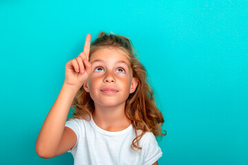 Wall Mural - A young girl with long brown hair is pointing up with her finger