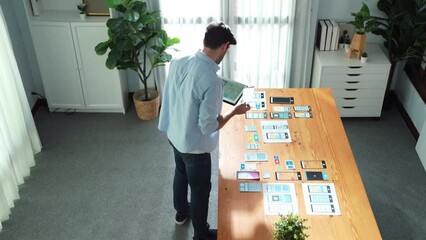 Top view of smart businessman holding tablet while looking at UX or UI design document at meeting table while analyzing data.Skilled manager choose idea or designing prototype or program. Convocation.