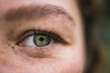 © Cavan Images - Close-up of a green eye with freckles and detailed features