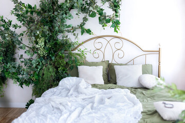 Wall Mural - House plants in the boho bedroom. Cozy light Scandi bedroom with flowers and plants decoration. Urban jungle interior design room at home. Soft pillows, blanket and linen on wrought iron bed.	
