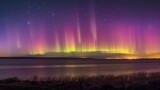 Fototapeta Tęcza - Breathtaking display of the northern lights in vivid colors stretching above a serene lake under starry skies