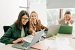 © Ilona - Young women work remotely using laptops while sitting in a meeting room in a modern office.