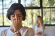 © insta_photos - Young woman meditating with eyes closed doing yoga pranayama breathing exercises holding fingers on face feeling energy during holistic healing yoga training class retreat session. Close up view.