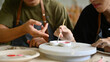 © saltdium - A close-up of Two students painting ceramic heart-shaped pieces with a brush together in an art studio. They work side by side, sharing tools and techniques, fostering creativity and collaboration