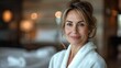 © Emile - headshot of happy smiling gorgeous middle aged woman in white bathrobe at spa salon hotel looking away advertising of bodycare spa procedures antiage recreation treatment concept