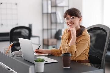 Canvas Print - Woman taking notes during webinar at table indoors