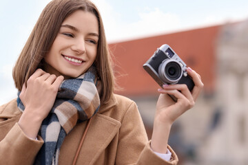 Wall Mural - Beautiful woman in warm scarf with vintage camera outdoors