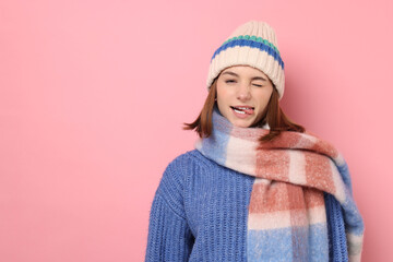 Wall Mural - Beautiful woman in warm scarf and hat on pink background, space for text