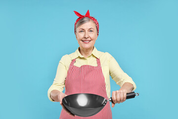 Canvas Print - Happy housewife with frying pan on light blue background