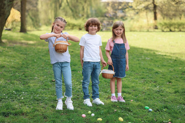 Wall Mural - Easter celebration. Cute little children with wicker baskets and painted eggs outdoors