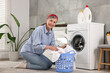 © New Africa - Happy housewife with laundry basket near washing machine at home