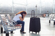 © Song_about_summer - flight delay or cancellation in airport, sad tired woman passenger waiting with luggage