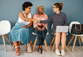 Canvas Print - People, waiting room with handshake and wall background, interview or chairs for appointment. Hiring, career opportunity or recruitment in modern office workplace, laptop and Human resource candidate