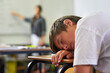 © peopleimages.com - Education, student and boy sleeping on desk, tired and bored in classroom, burnout and fatigue in school. Youth, child and kid with dream on notebook, table and lazy for knowledge, rest and relax