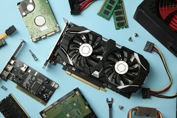 Poster - Graphics card and other computer hardware on light blue background, flat lay