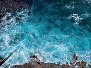 Wall Mural - Aerial photo of a sea water surface. Turquoise blue water with white foam on waves - view from above. Stylized background abstract texture photo. Tenerife, Puerto de la Cruz