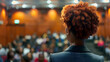 © Thumbs - Black speaker giving a presentation in the university workshop hall. Auditorium or conference room. Back view. Scientific conference event, training