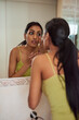 © peopleimages.com - Woman, skincare and mirror face in bathroom in cosmetics, moisturizer and touch with makeup. Girl, clean for hydration and female Indian, selfcare and foundation for home morning grooming routine