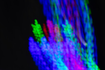 Wall Mural - a blurry image of a colorful light display with a green and red flower. the image has a dreamy, ethe