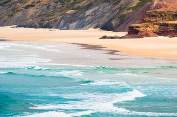 Wall Mural - Waves on the coast of Atlantic ocean in Algarve, Portugal. Beach with yellow sand and turquoise water.