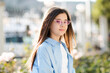 © morrowlight - Stylish teenage girl 10 - 12 year old wearing sun glasses and blue shirt posing over nature sunny background. Looking at camera. Summer vacation season.