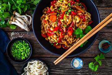 Wall Mural - Asian style stir fried vegetables and noodles on wooden table
