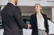 © anatoliycherkas - Salesman or manager gives keys and shakes hand to new car owner in car dealership