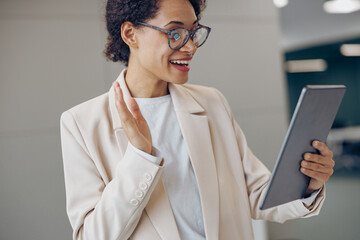 Wall Mural - Smiling female freelancer talking with colleague via video call while standing in modern coworking