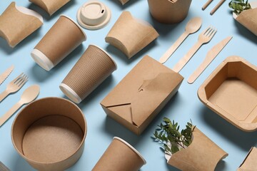 Wall Mural - Eco friendly food packaging. Paper containers, tableware and green twigs on light blue background