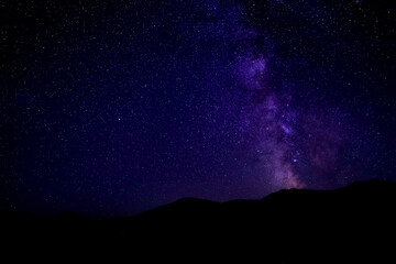 Wall Mural - Sky with twinkling stars over mountains at night