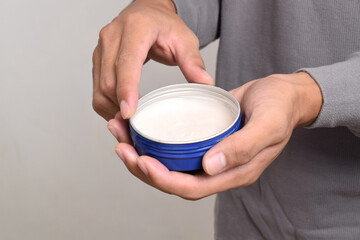 Man's hand holding pomade or waxe for hair styling isolated on white background