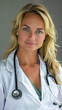 © AstraNova - portrait of beautiful confident friendly middle-aged female doctor with blonde hair smiling wearing white uniform and stethoscope on hospital clinic background