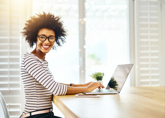 Wall Mural - Portrait, laptop and black woman with glasses, typing and copywriting on desk, startup and online. Morning, employee and person with computer, keyboard and research of website of blog in home