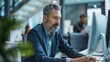 © Adobe Contributor - Focused Middle-Aged Business Professional Working on Desktop Computer