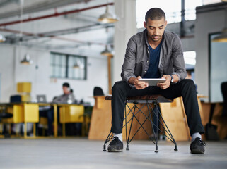 Fototapete - Creative, man and reading on tablet in office with research for app development, website layout or data update. Designer, internship or person with tech on chair in coworking workplace to monitor SEO